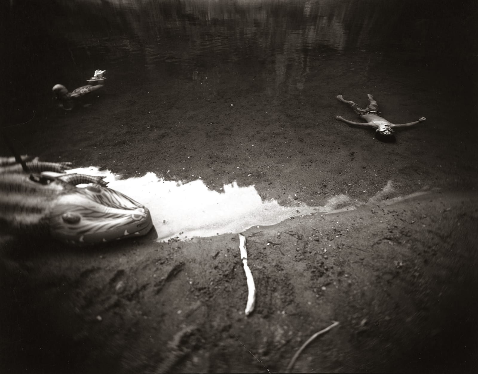 Emmett floating in river with alligator raft, from the Immediate Family series by Sally Mann