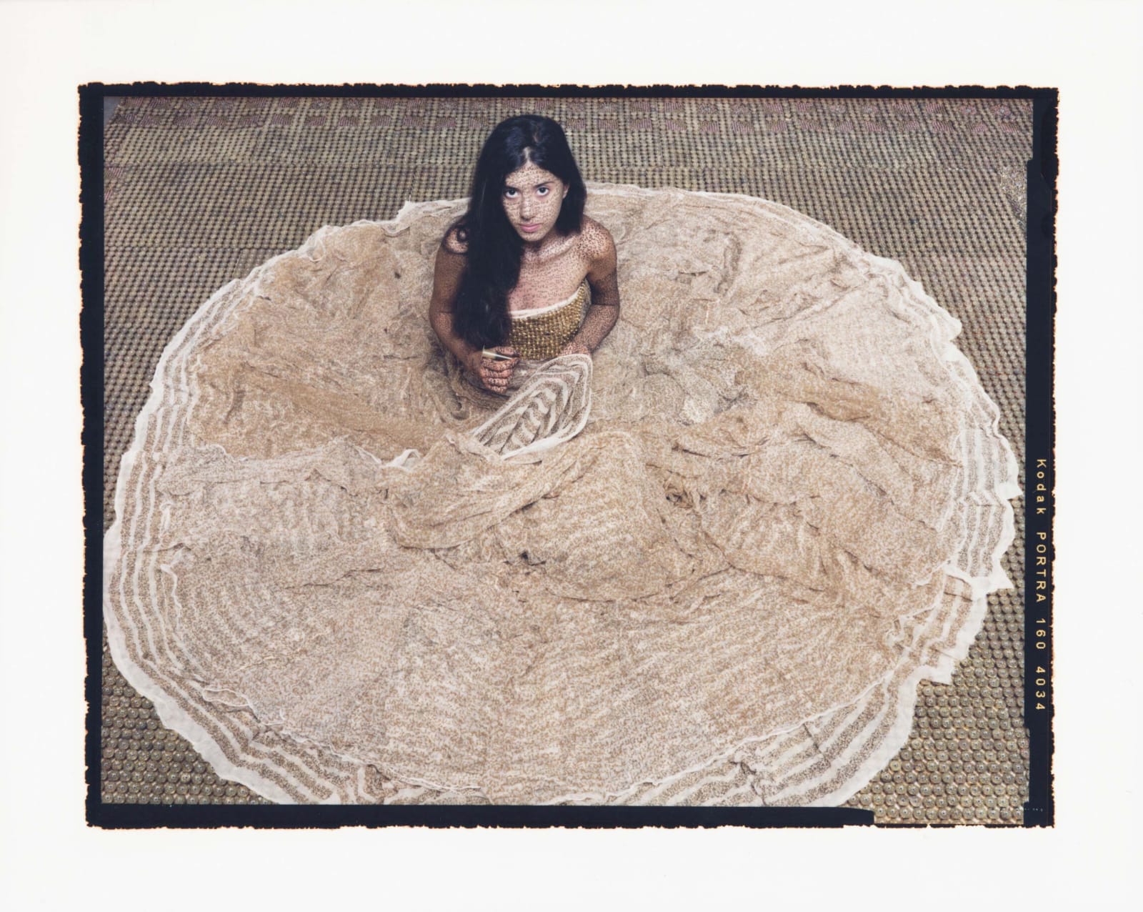 Woman sitting on floor with dress in circle around her, holding henna in hand, by Lalla Essaydi