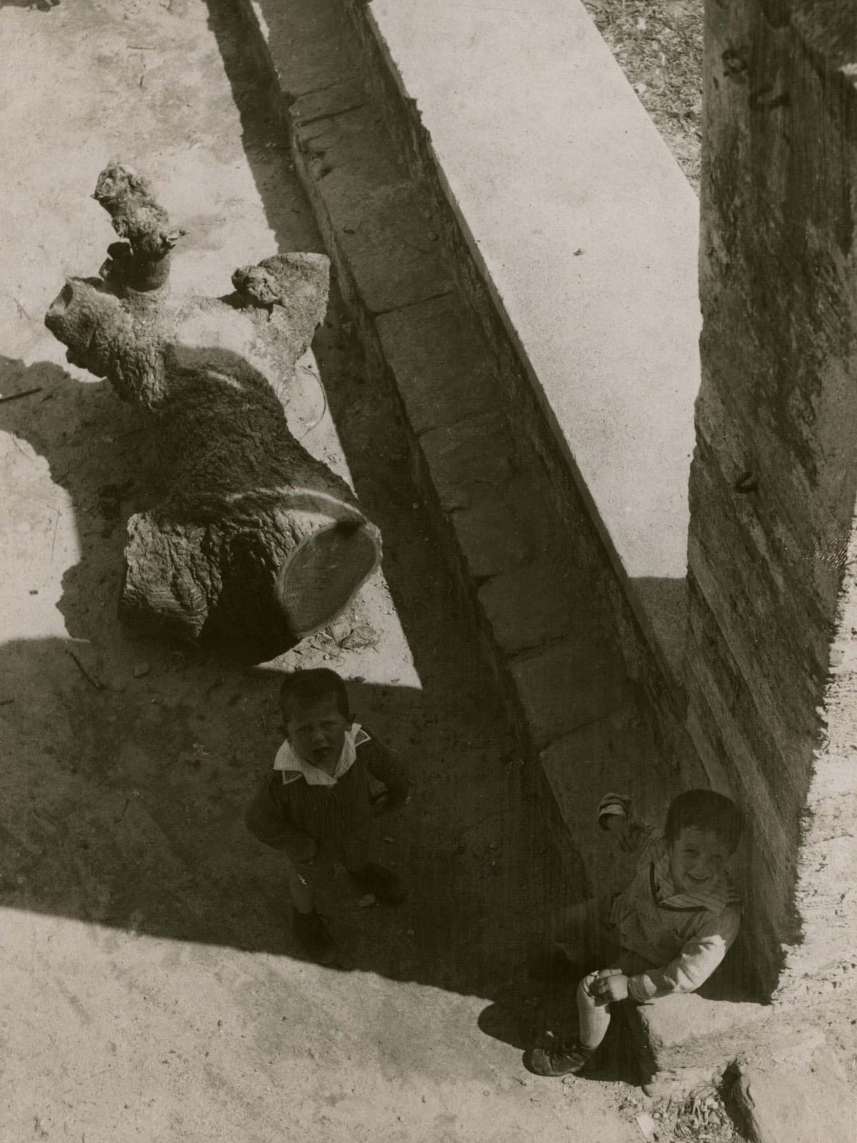 Laszlo Moholy-Nagy Kinder in Ascona two children sitting on dusty road next to cut tree trunk and brick column