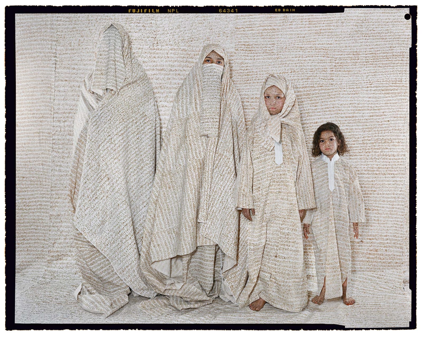 Lalla Essaydi, Converging Territories #30 four generations of women wearing traditional clothing in various stylings, fabric inscribed with Arabic calligraphy in henna