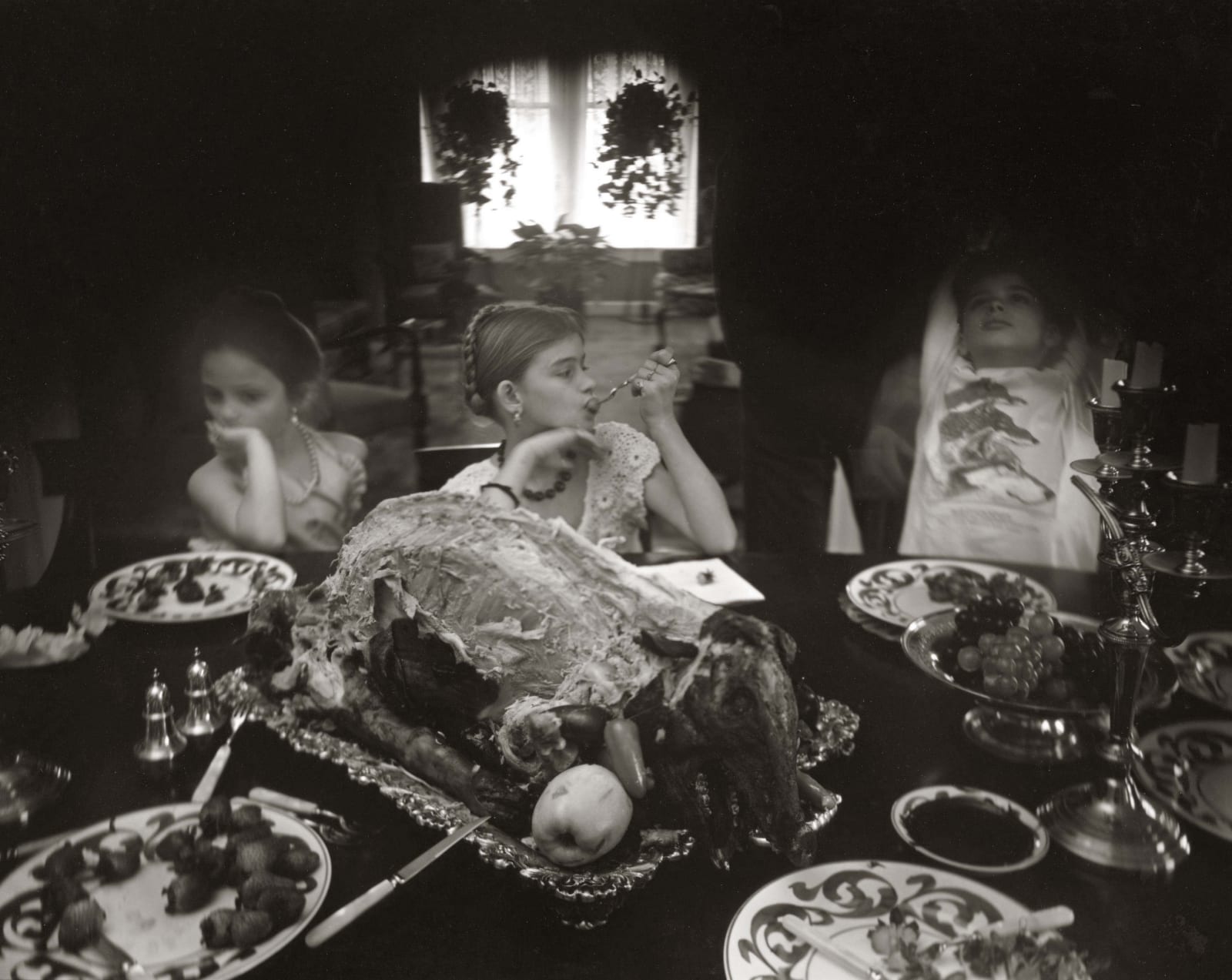 Jessie, Virginia and Emmett feasting on roast pig a la three wolves, from the Immediate Family series, by Sally Mann
