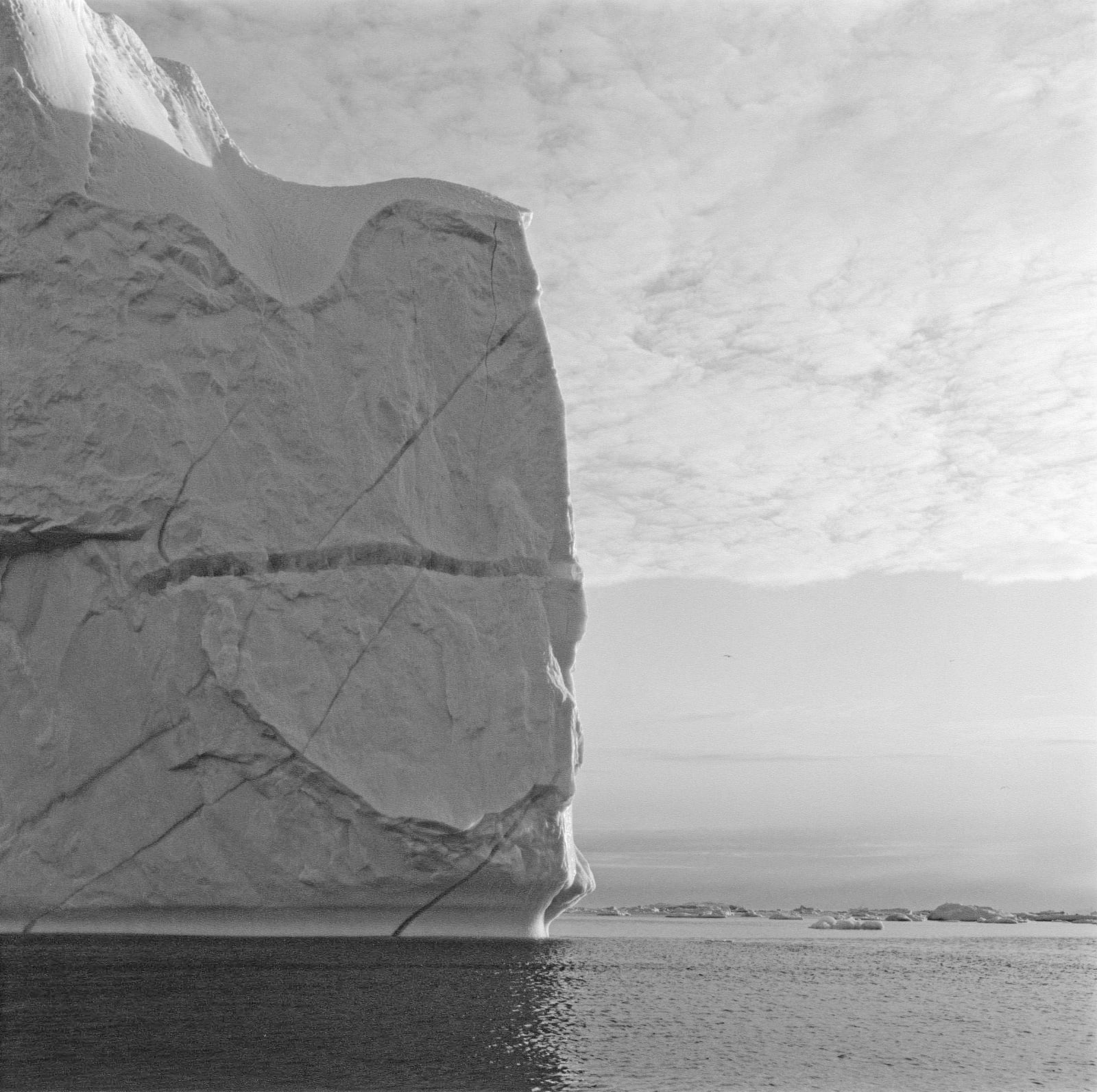 Lynn Davis photograph of iceberg in Disko Bay, Greenland, with horizontal cleft in alignment with clouds in sky