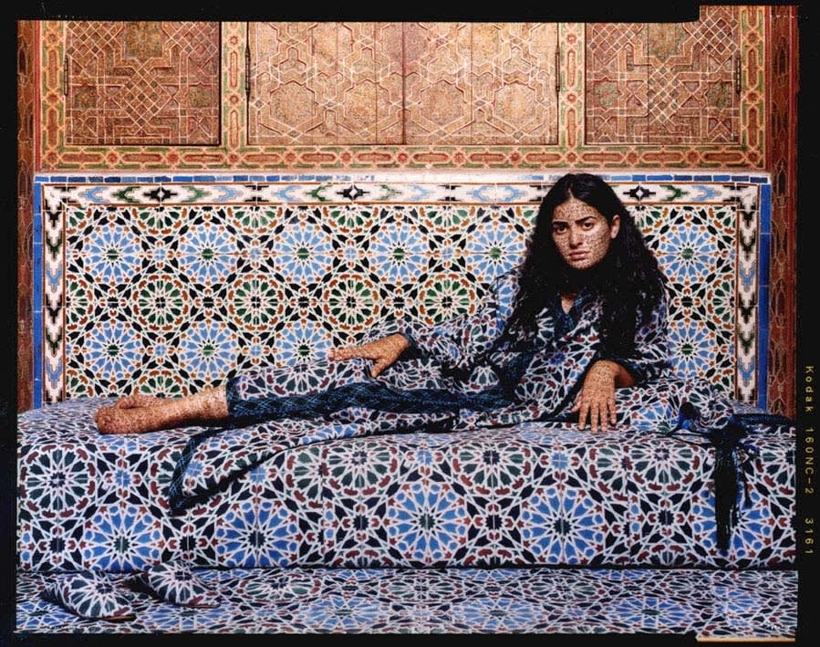 Woman reclining against tiled and wood wall, by Lalla Essaydi