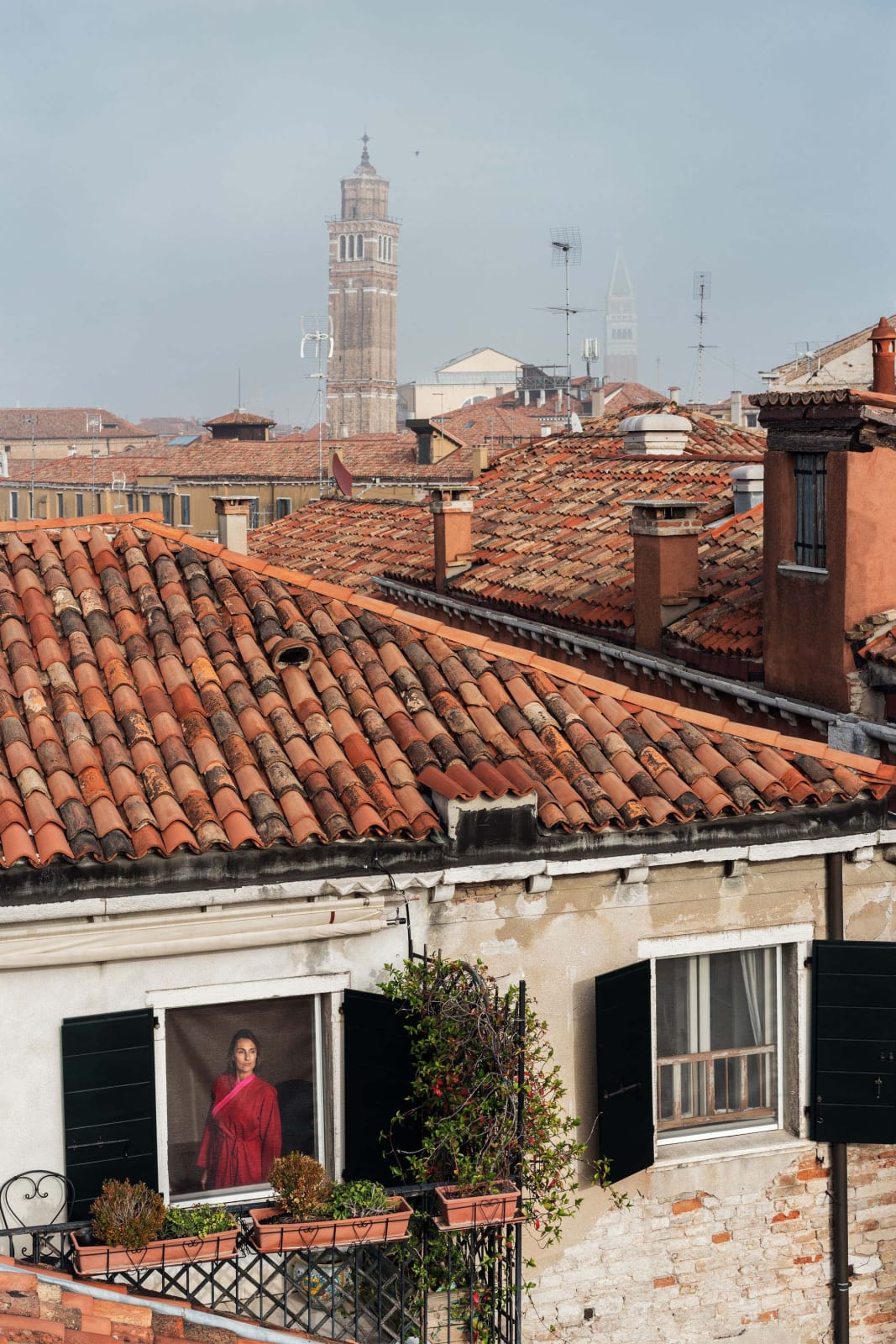 Gail Albert Halaban Out My Window Italy Italian Views Out My Window, Red Kimono, San Marco, Venice, October, 2017 woman in window in red robe orange tile rooftops and church spire in distance