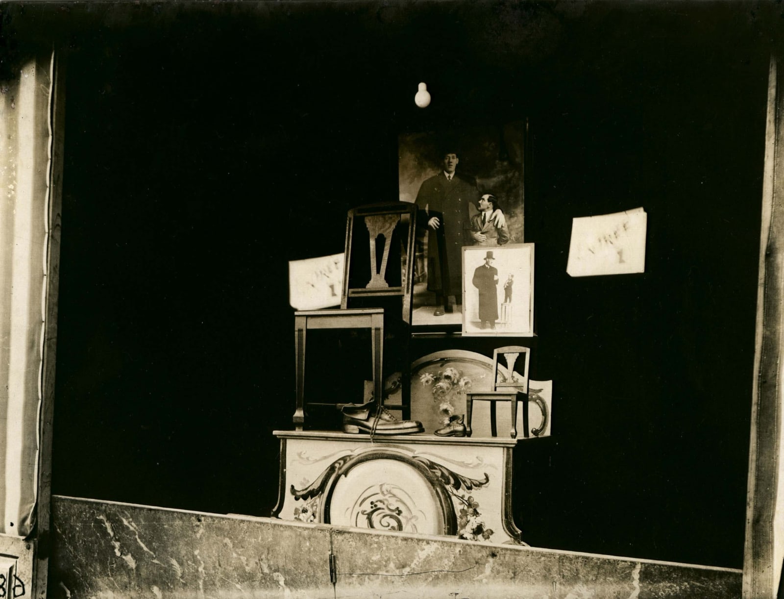Eugene Atget black and white photograph of a window display of chair and shoes for giant and midget
