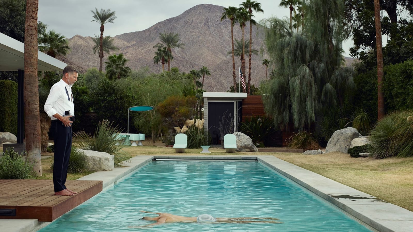 Self-portrait of Erwin Olaf holding a camera and looking at man in pool in Palm Springs