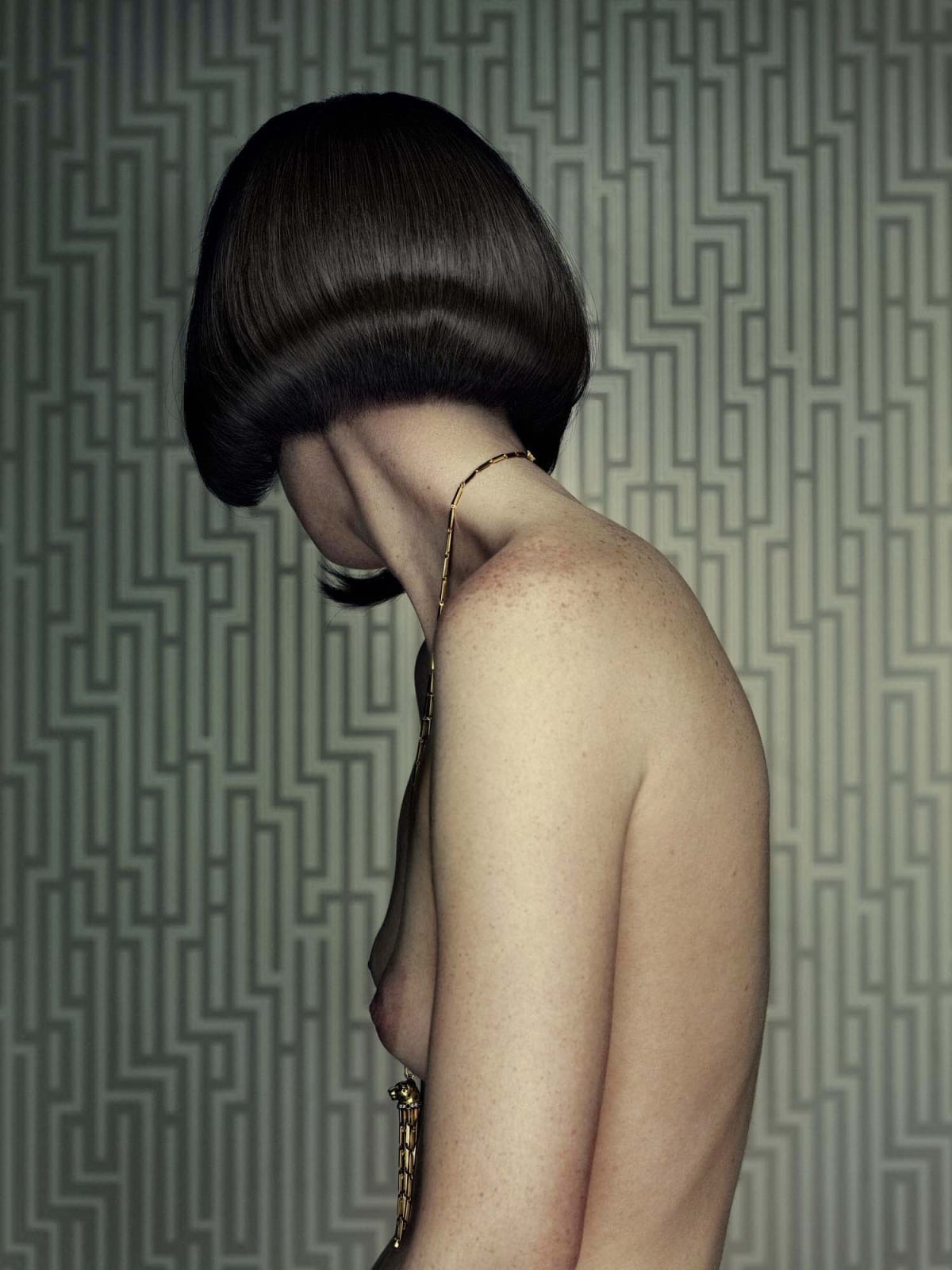 Erwin Olaf portrait of woman from Keyhole series, nude woman with bob haircut turned away from camera with geometric wallpaper in background