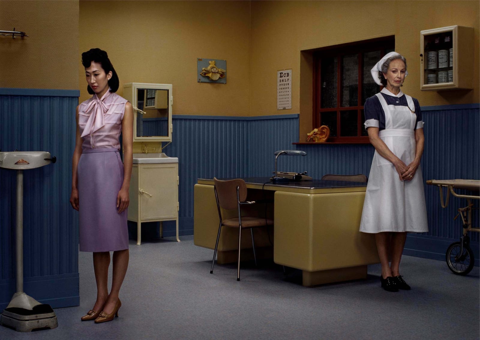 Erwin Olaf photograph of woman in doctor's office with nurse standing on other side of the room