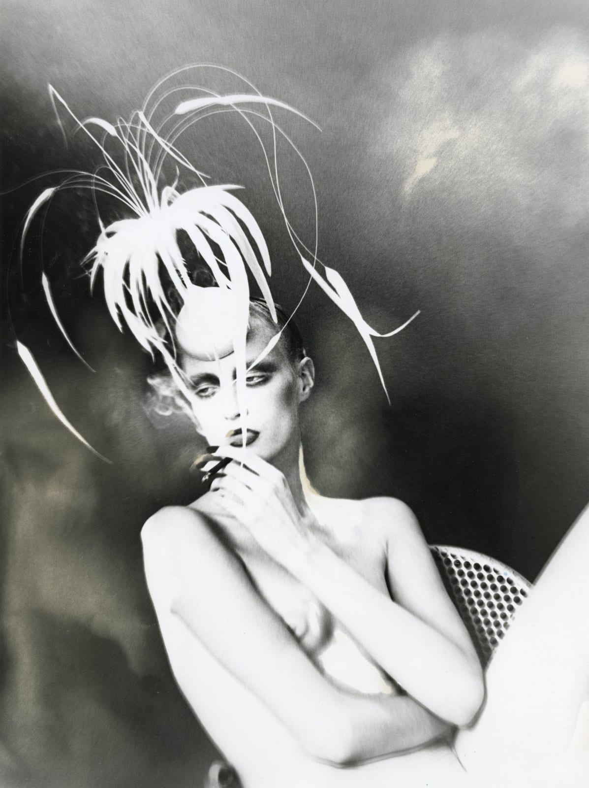 nude woman in high-fashion feathered hat smoking cigarette by Lillian Bassman