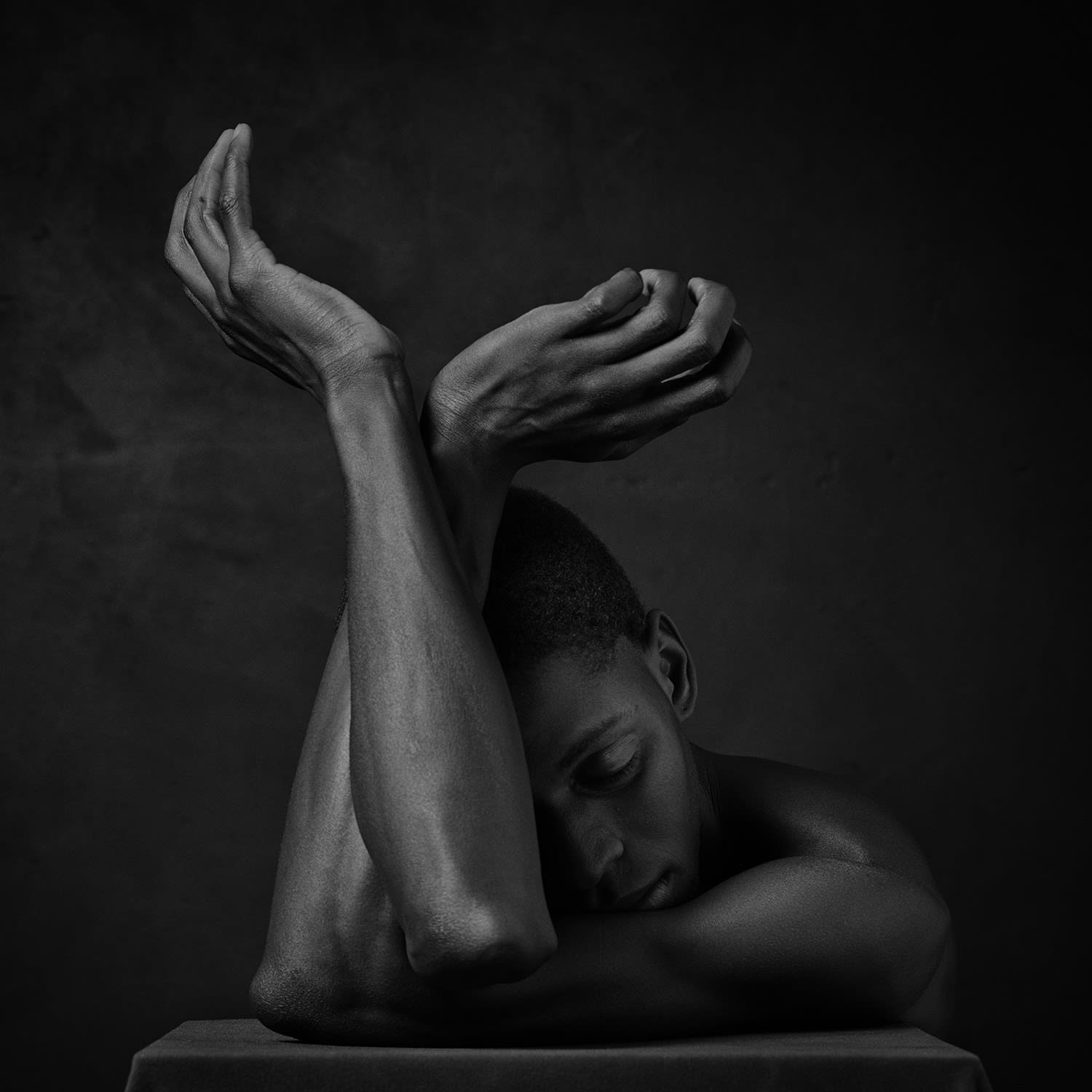 Erwin Olaf photograph of male black nude with forearms crossed and head in crook of elbow
