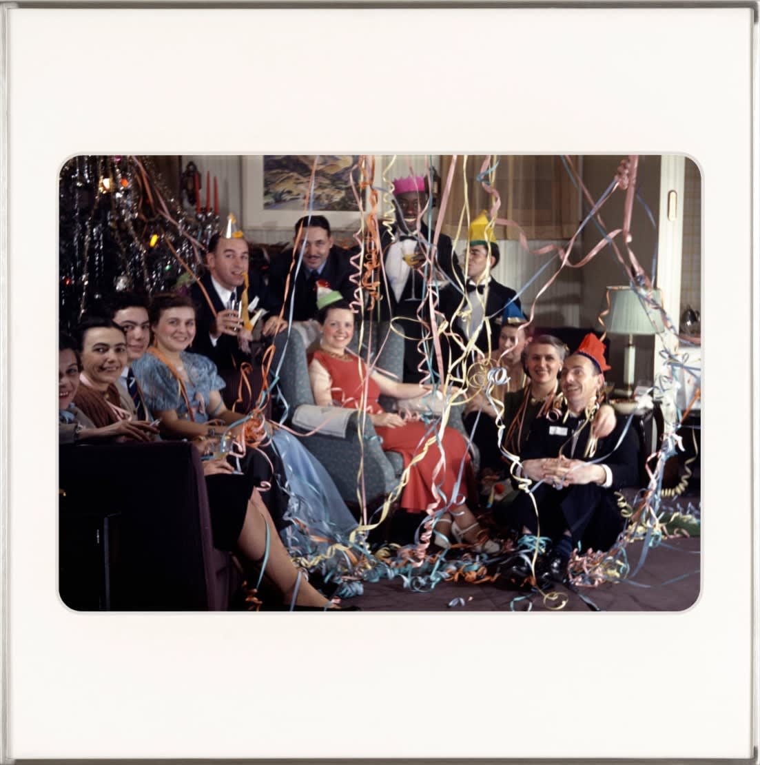 A group shot in a living room with party streamers hanging everywhere. By Lee Shulman & The Anonymous Project.