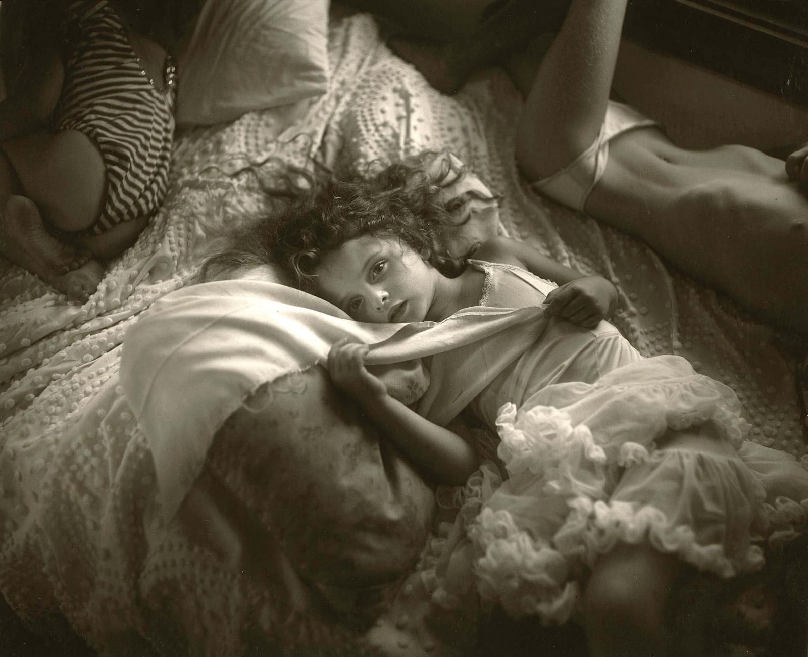 Sally Mann Naptime Virginia in tutu lying on bed looking at camera holding a white blanket with two other girls lying on bed