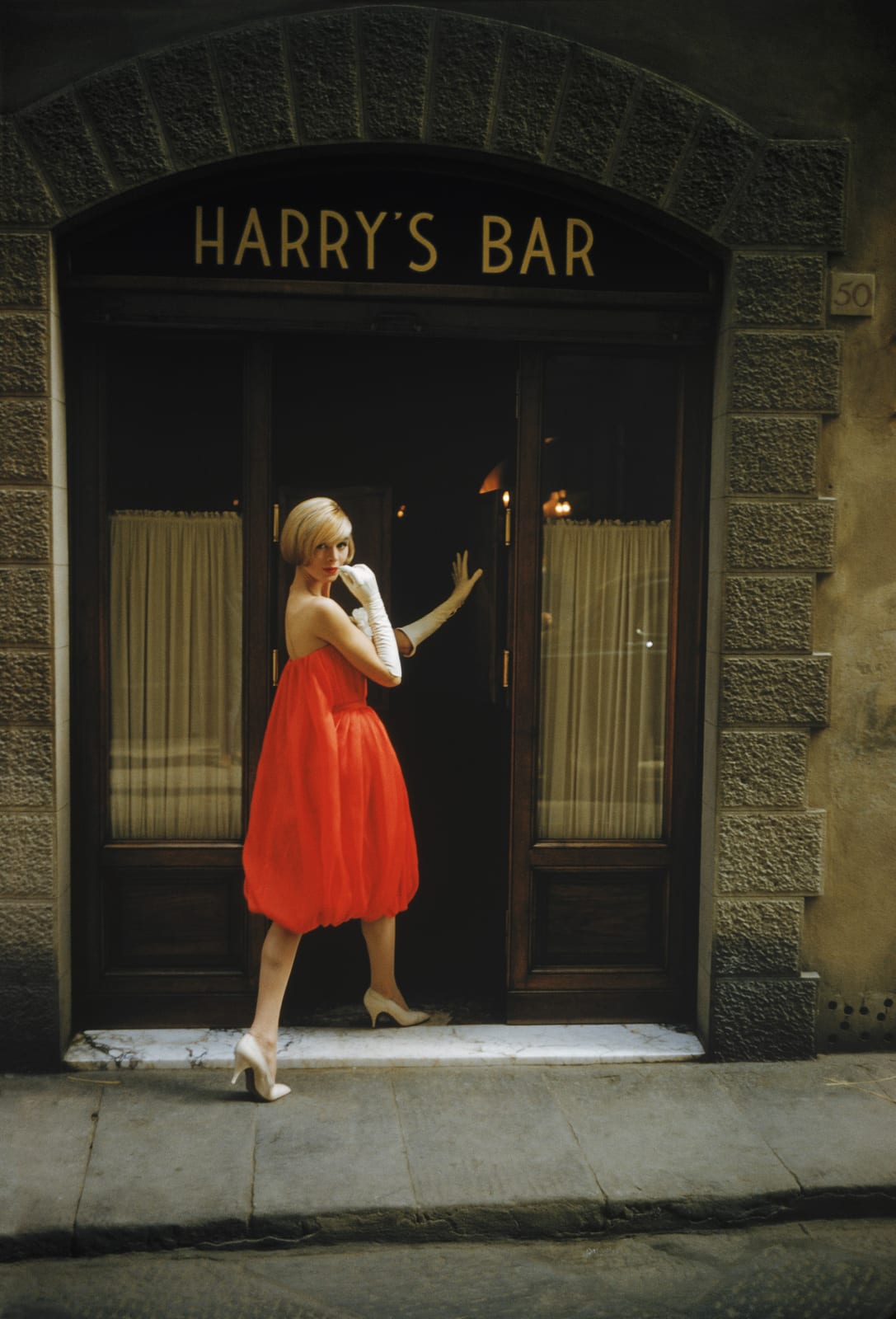 Mark Shaw, A model wearing a Fabiani "Bag" dress is photographed outside Harry's Bar in Florence, Italy in Via del Parione, 1957