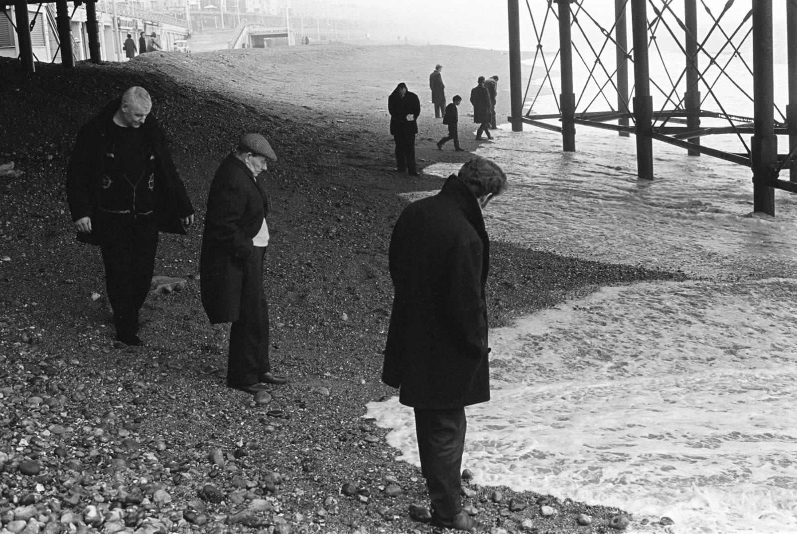 Homer Sykes, Blacksanding, sunday morning, under Brighton Pier looking for coins that are washed up, Brighton, Sussex, 1970