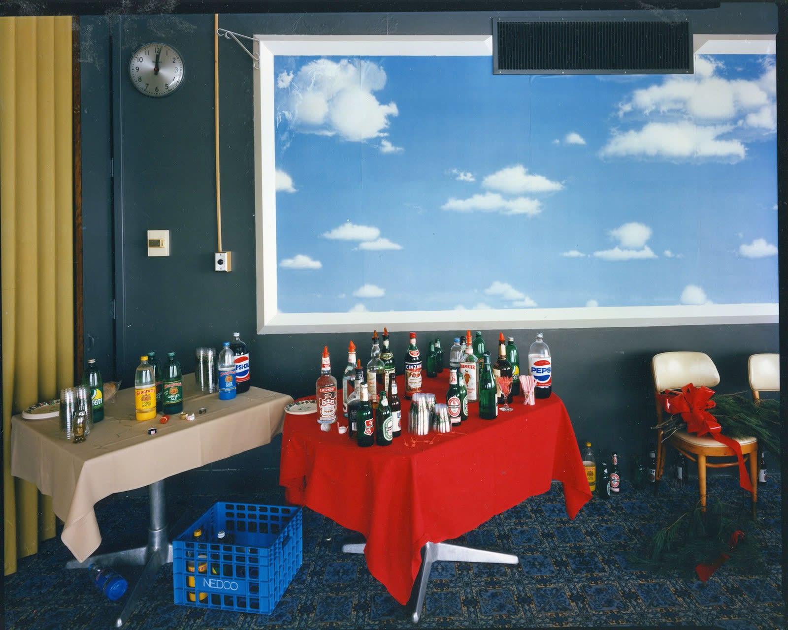 Bruce Wrighton, Framed clouds with blue sky, over 2 tables with soda/liquor bottles (red and tan tablecloths)