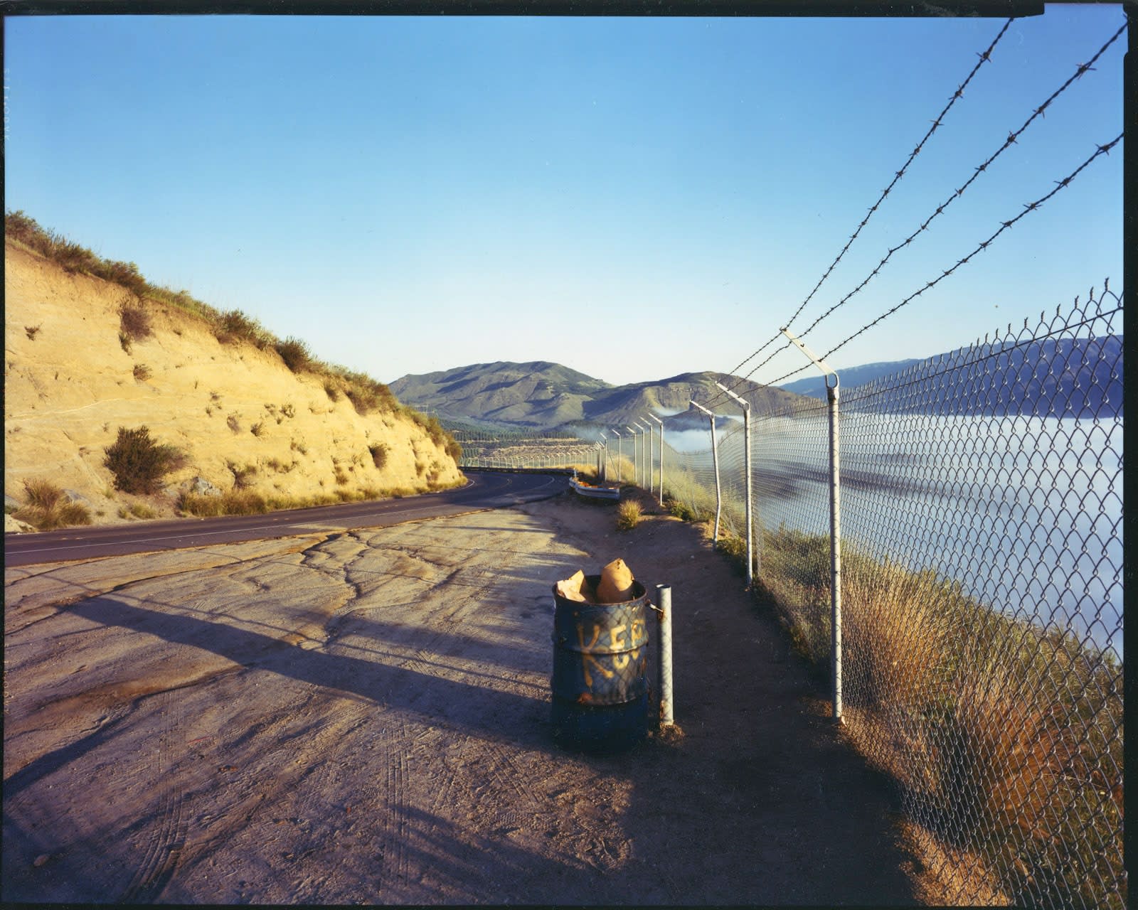 Bruce Wrighton, Hills in distance, eastern berm on left, chian-link fence on right, trash can center