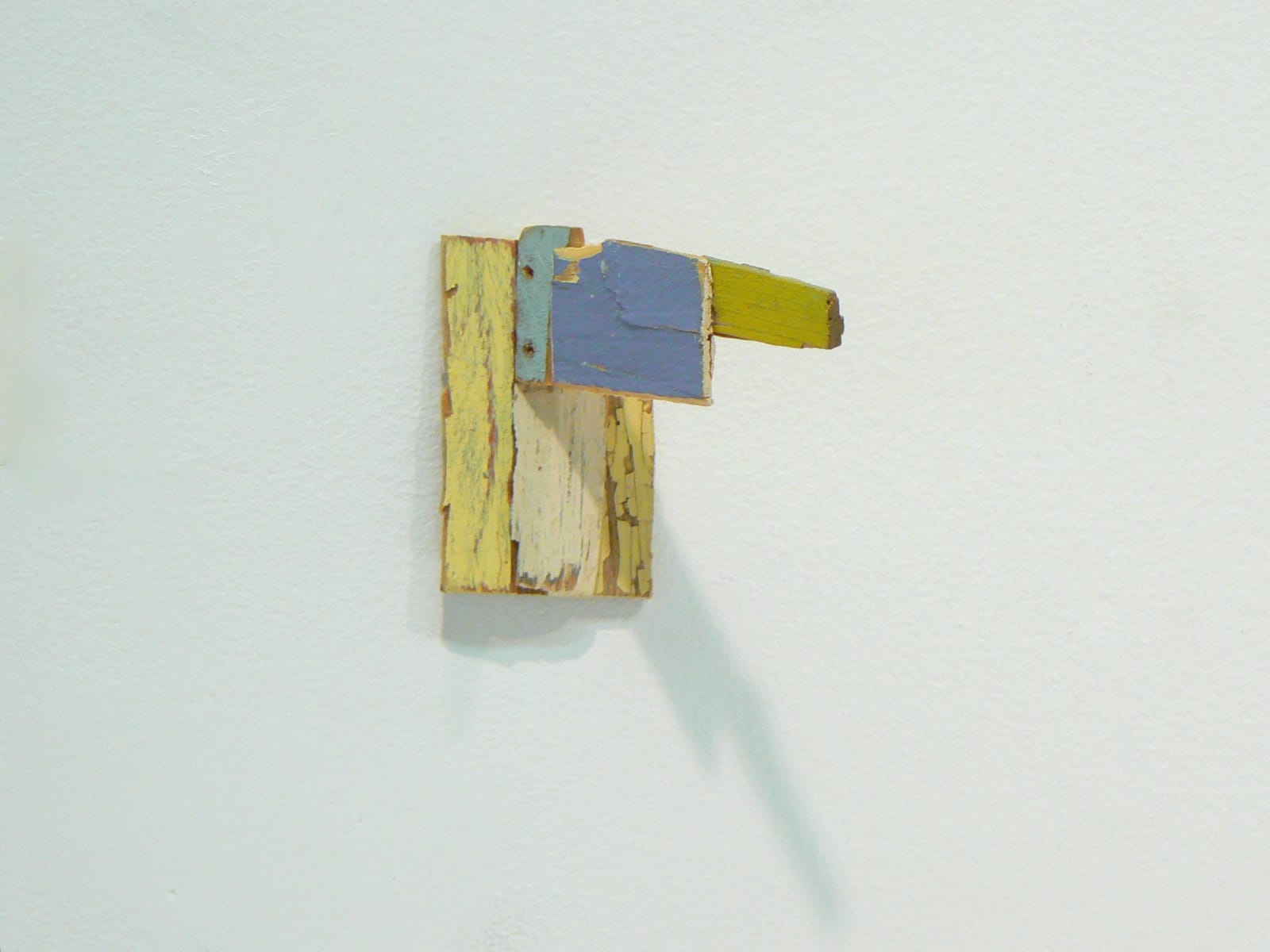 abstract wooden wall sculpture with gray and yellow paint. Projects off the wall.