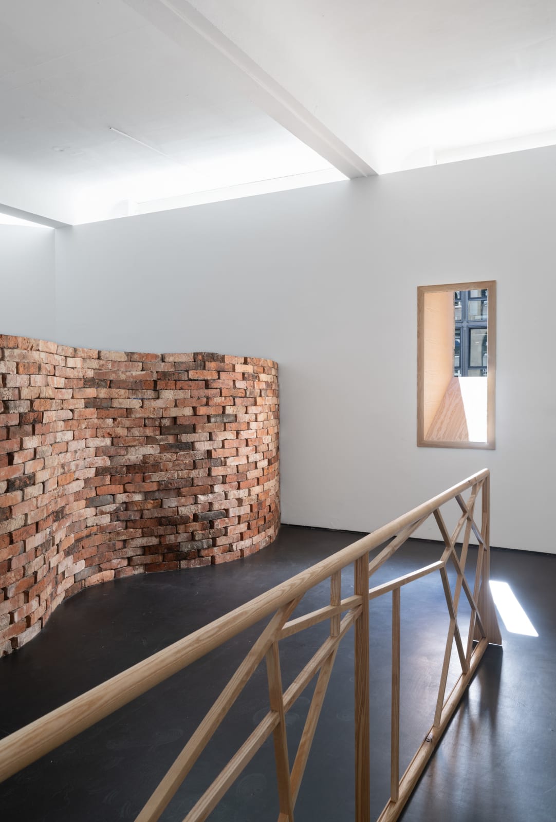 Partial view of wooden railing structure with vertical horizontal wooden balance beams running through it and and a brick wall behind it as well as a window with an angular wooden frame. Rindon Johnson Fruit of the poisonous tree, Higher and more free! The music must always play, All the conventions conspire to make this fort assume the furniture of home; Lest we should see where we are, higher and more free! Lost in a haunted wood, What are the consequences of two different forms interacting? Ice on a bed of mint leaves. That’s what I thought in the early morning. Higher and more free! Breeze engine. If no is what it is then that’s what it is. Breeze Engine. Paint dries on walls. Bells chime at noon. Rivers flow through canyons. Enough. Enough. Enough. Enough. Enough., 2023 Ash wood 420 x 67.5 x 16.5 cm 165 3/8 x 26 5/8 x 6 1/2 inches