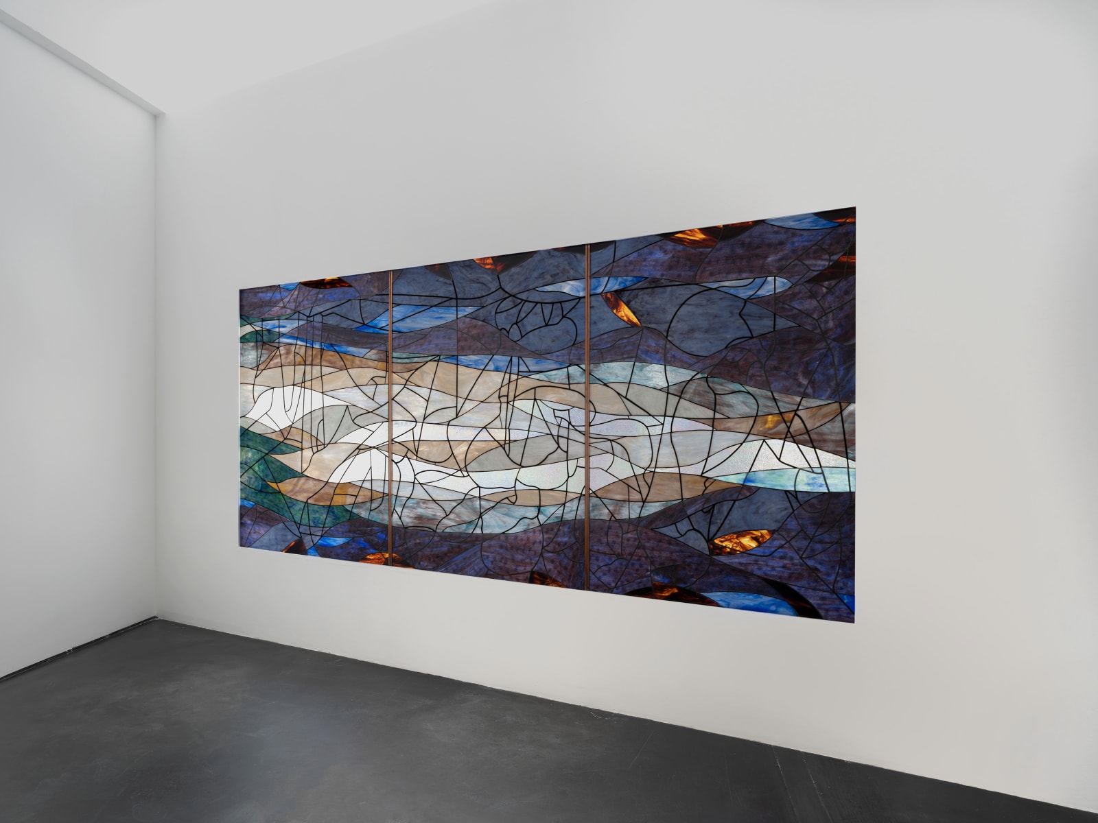 Room with a dark blue, green and orange stained glass window made up of 3 panels against a plain wall Rindon Johnson Clattering, 2021 Stained glass work (3 panels) and ash wood bench Glass work: 360 x 158 cm 141 3/4 x 62 1/4 inches Bench: 200 x 49 x 80 cm 78 3/4 x 19 1/4 x 31 1/2 inches