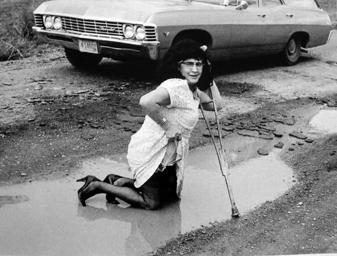Stan Healy, Cross dress self portrait with crutch in puddle