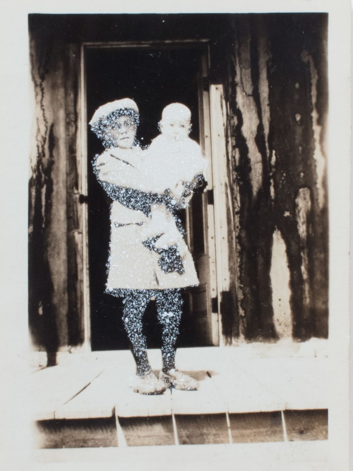 John Latour, Young boy in coat and cap holding a baby in his arms, 2015