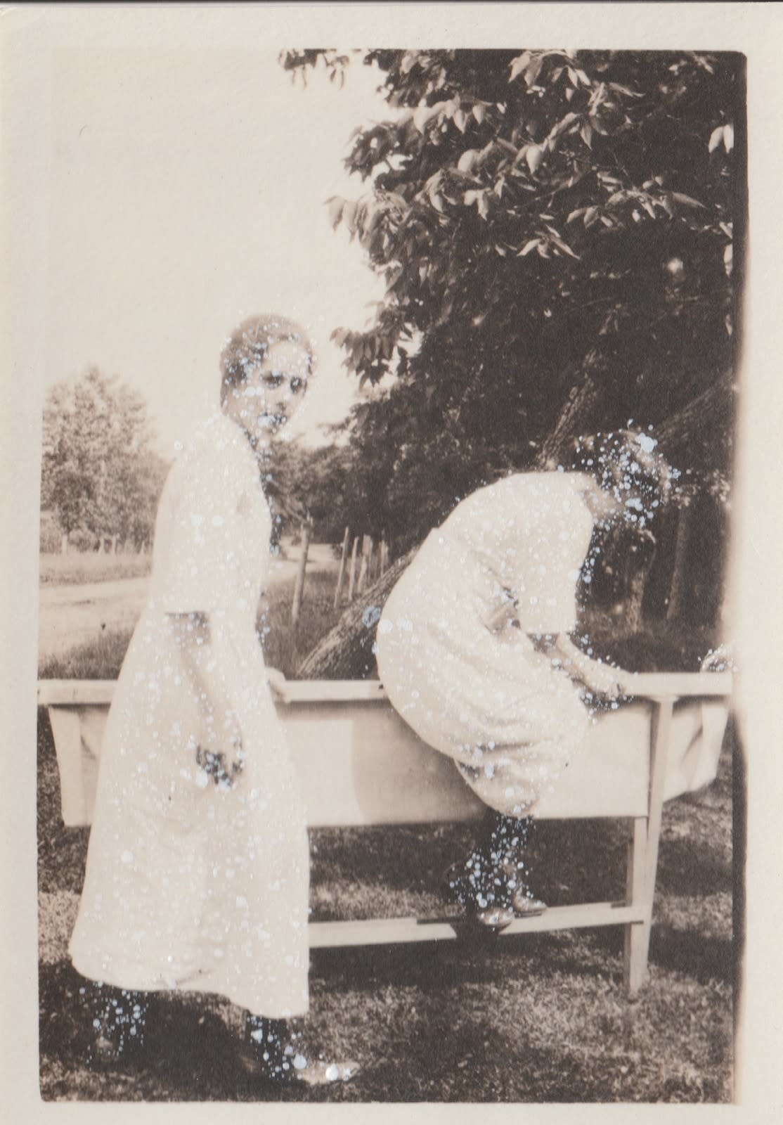 John Latour, Two Women in White Dresses and Black Boots, One Climbs over a Curious Structure, 2021