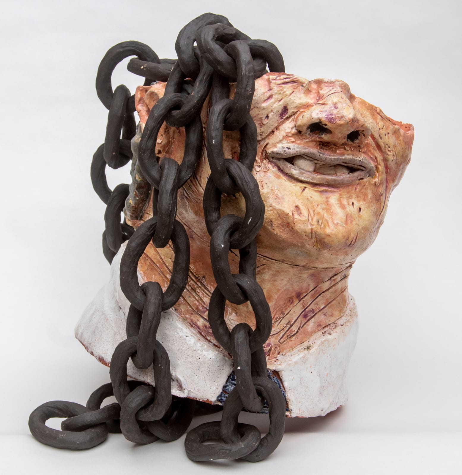 A sculpture of a face from the nose down with large chains hanging from inside by artist Reniel Del Rosario.