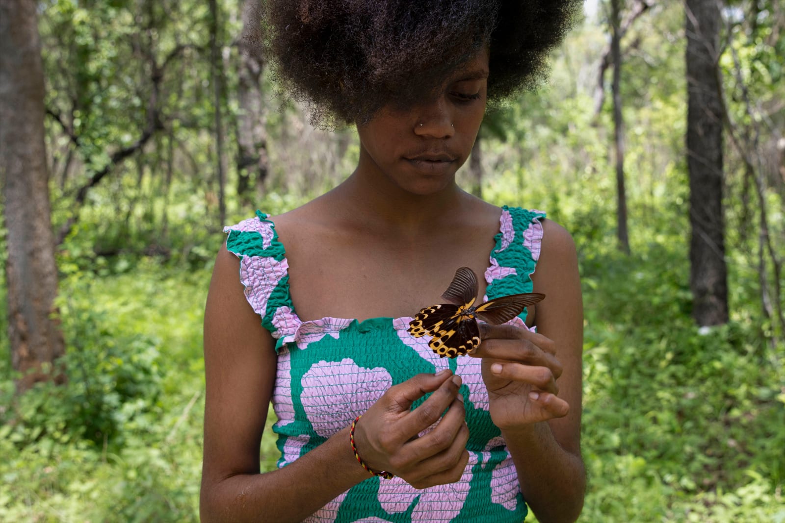A girl in the forest with a butterfly in her hands. Photography by Aboriginal-Australian artist Naomi Hobson.