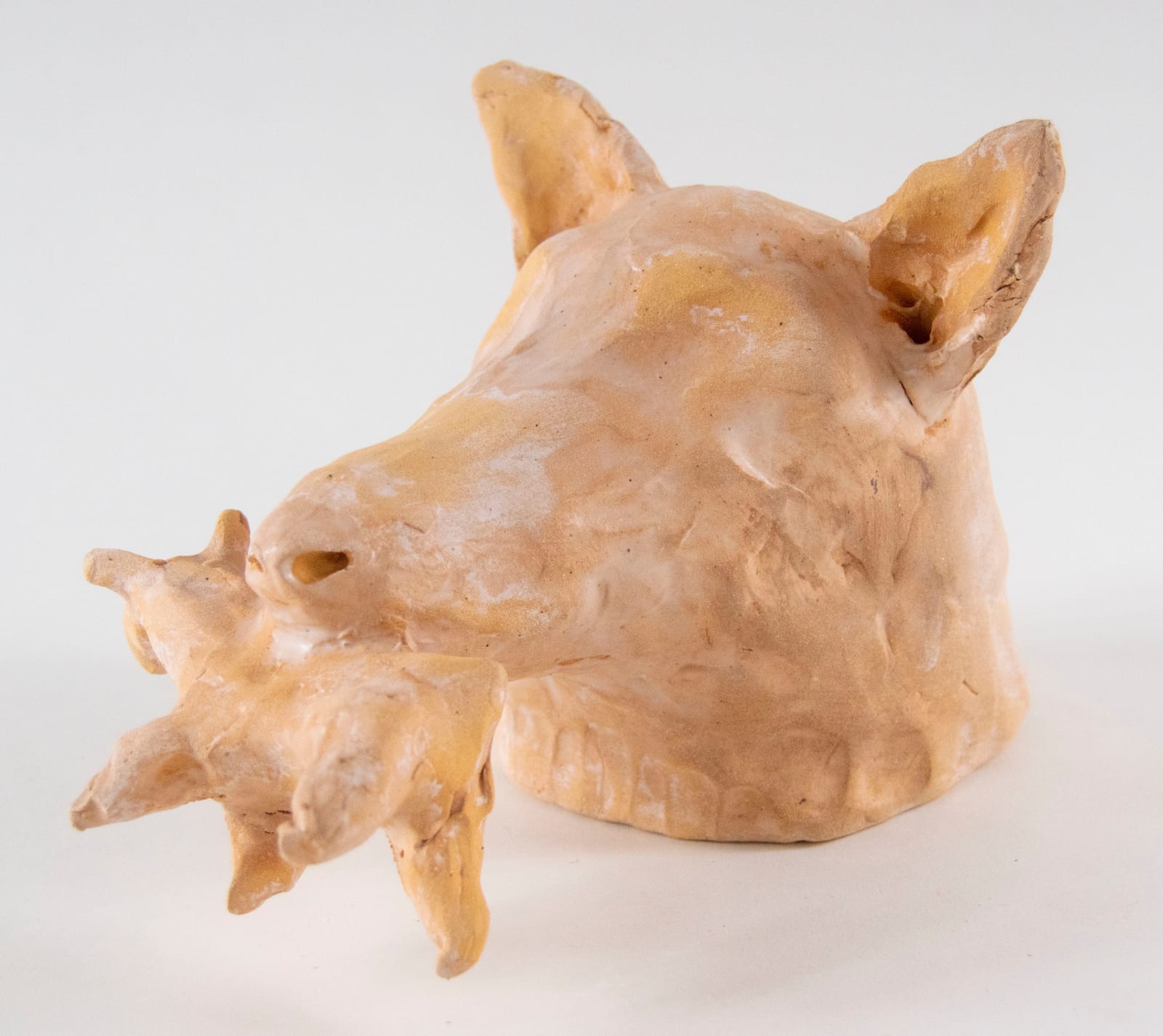 A sculpture of a dog head with a small dog in its mouth by artist Reniel Del Rosario