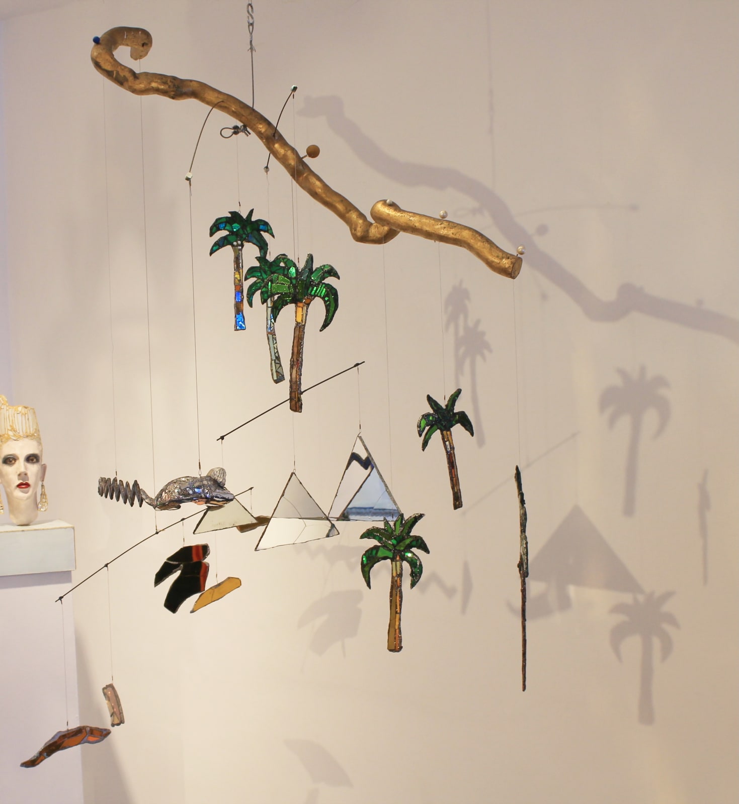 A colourful, glittering sculpture by Andrew Logan inspired by ancient Egypt, featuring gold, mirrors, and jewel-like decorations shaped like pyramids and palm trees.