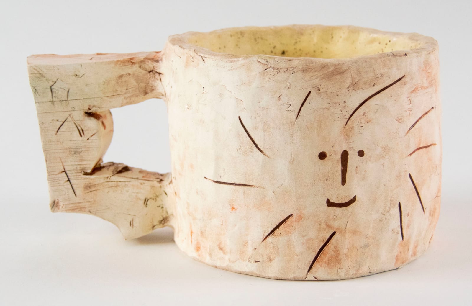 A mug with a smiling face on the side by artist Reniel Del Rosario.