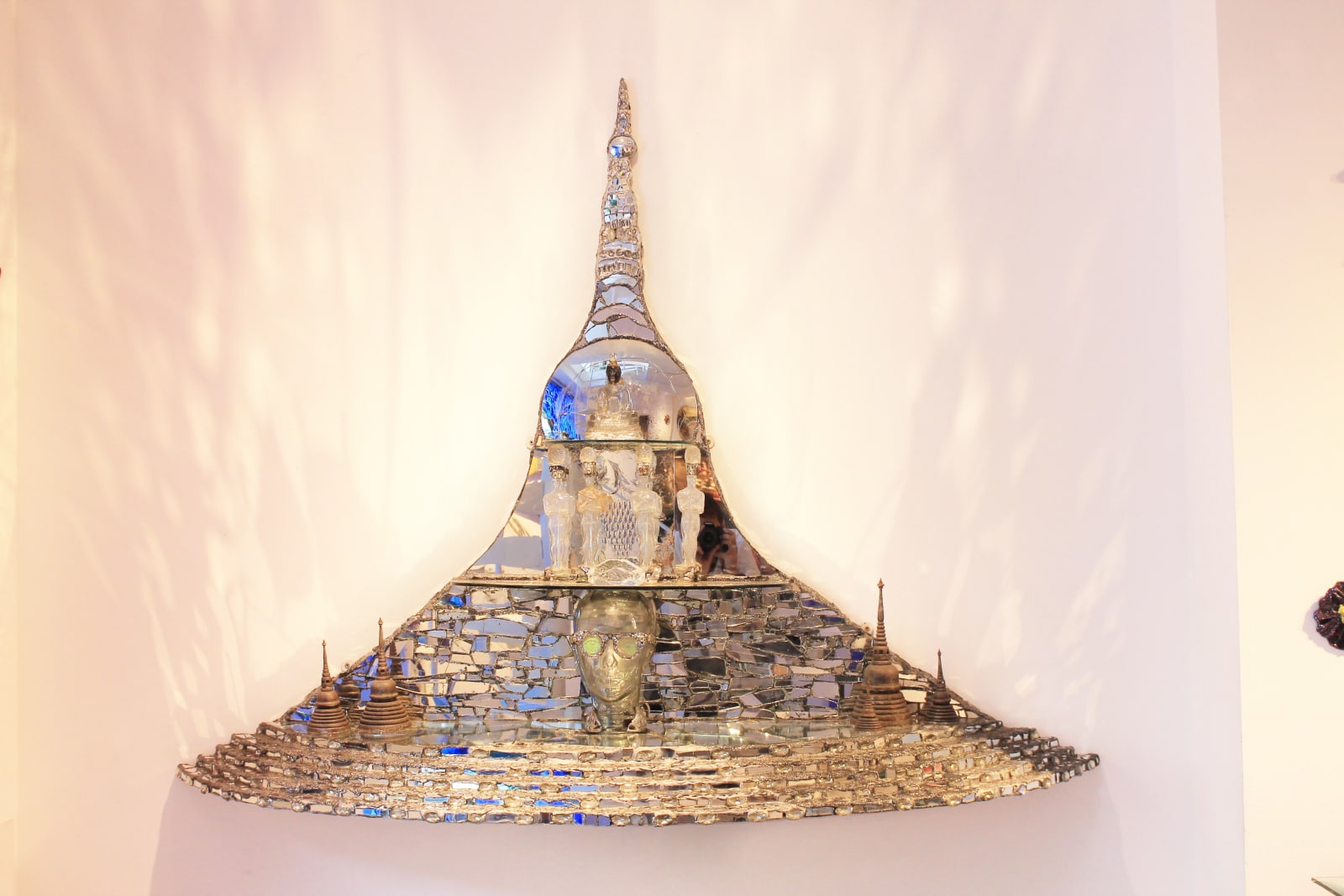 A sparkling sculpture by Andrew Logan called Eventuality, made with mirrors, glitter, and metallic shapes. The artwork shows flowing, abstract forms that suggest time, change, and movement, in Logan’s bright and joyful style.