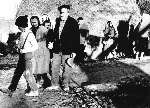 Mario Giacomelli, La Buona Terra 141 (peasants walking past hay stack), 1964