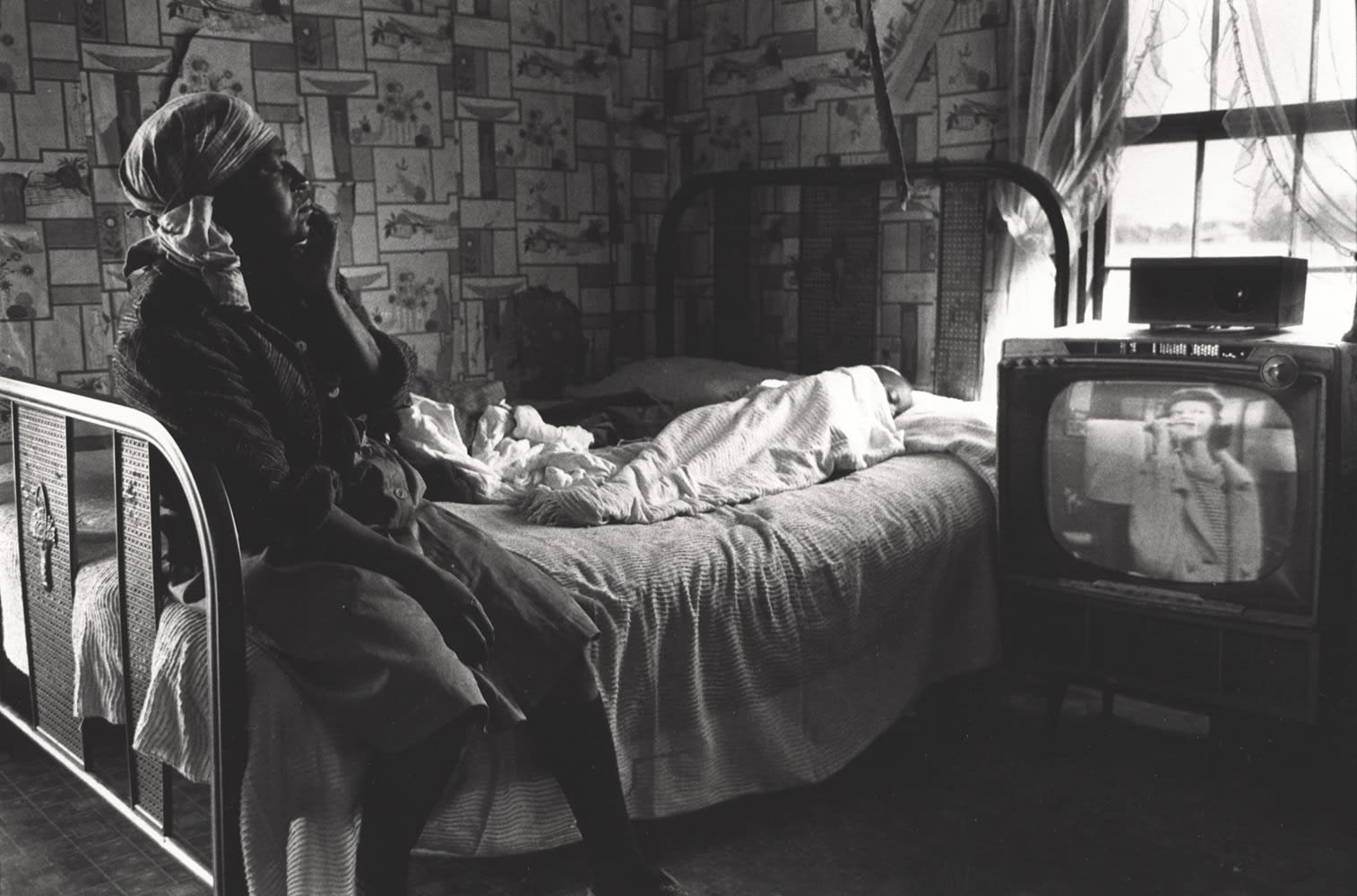 Constantine Manos, Untitled, Sharecroppers, South Carolina (lone woman on bed watching tv), 1965