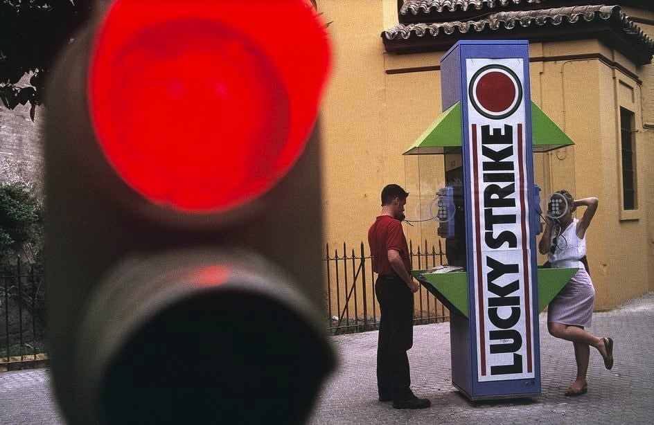 Alex Webb, Seville, Spain (two people at Lucky Strike phone booth), 1992