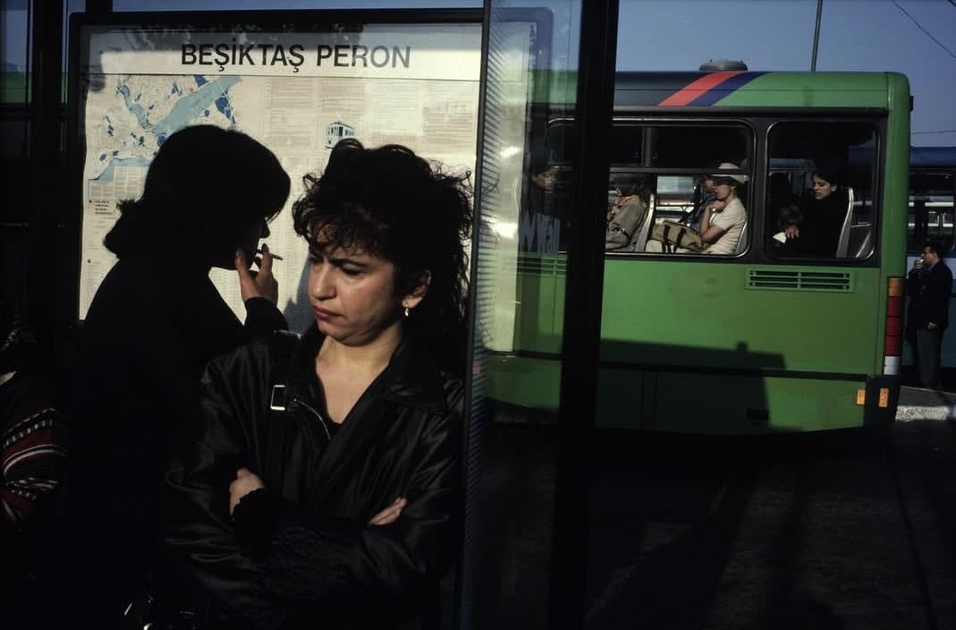 Alex Webb, Istanbul (two women around bus stop/green bus), 2001