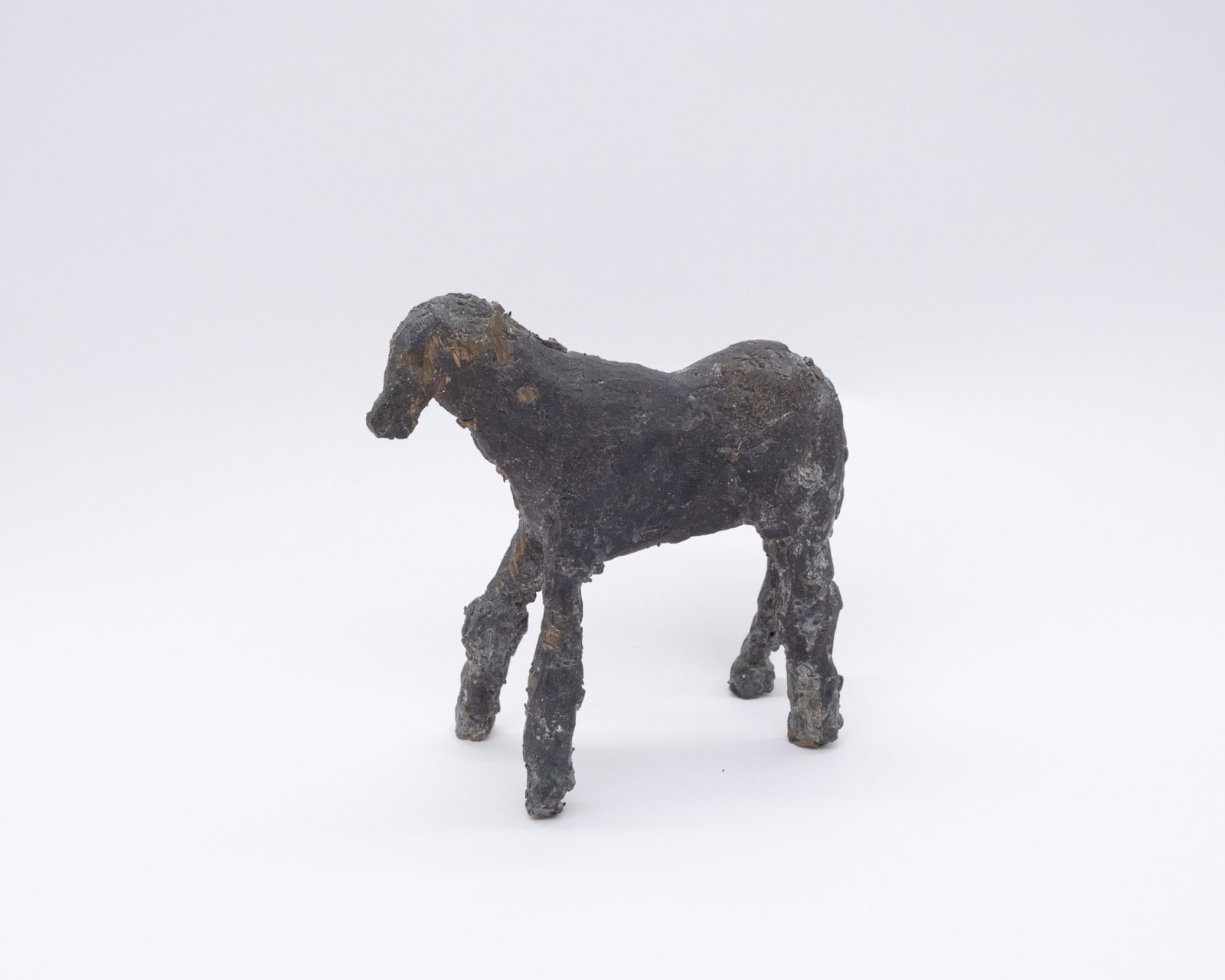 A cast bronze sculpture by Susan Bowers of a rough abstracted horse.