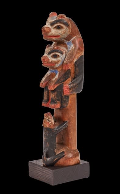 A pigmented wood Tlingit potlatch carving of a wolf chasing two bear cubs up a tree, 1890