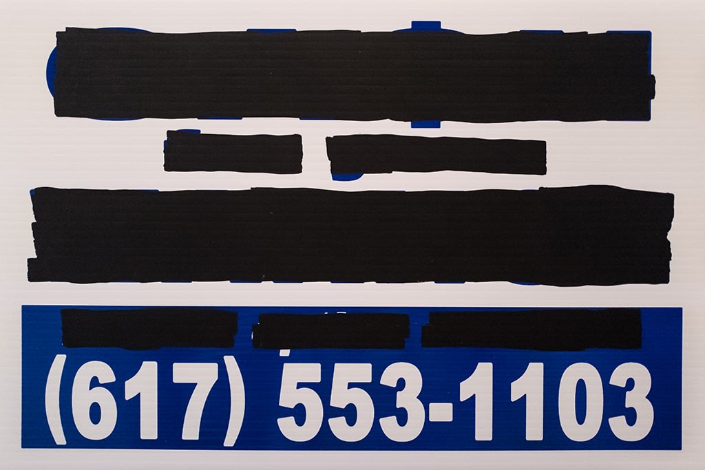 redacted sign reading a telephone number