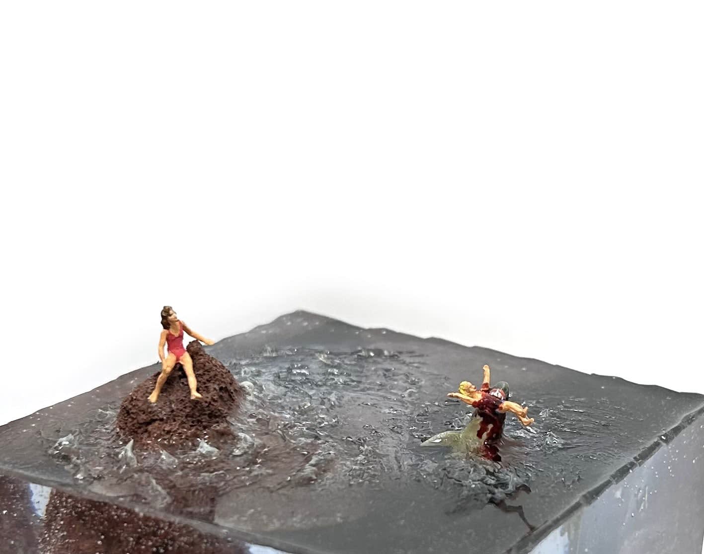 sculpture of a woman on a rock and another woman being eaten by a shark in the water