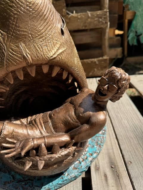 sculpture of a shark with a man in his mouth