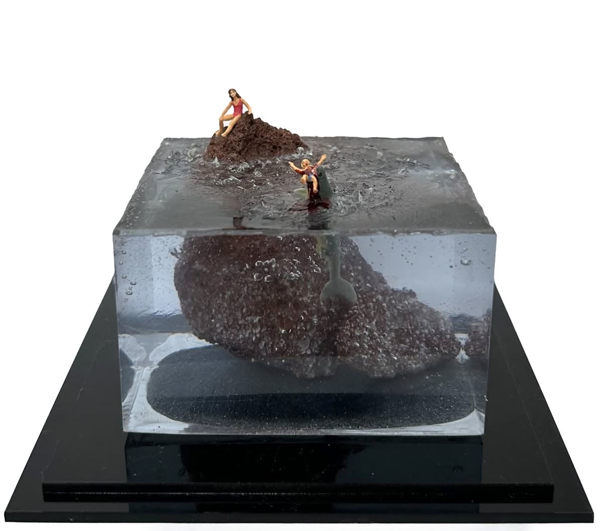 sculpture of a woman on a rock and another woman being eaten by a shark in the water