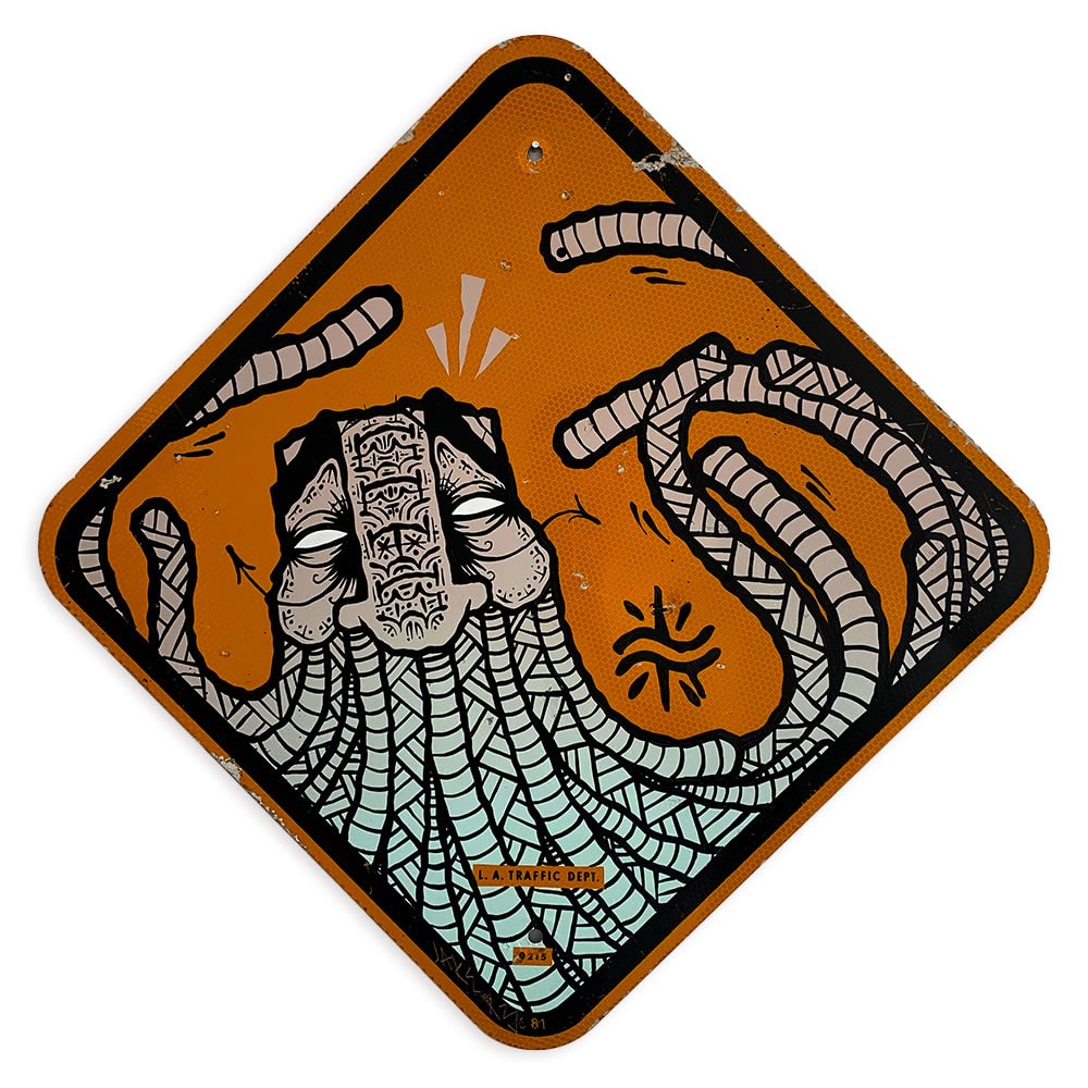 Orange road sign with detailed illustration of a masculine face, long beard, and intricate symbols/patterns in around the face.