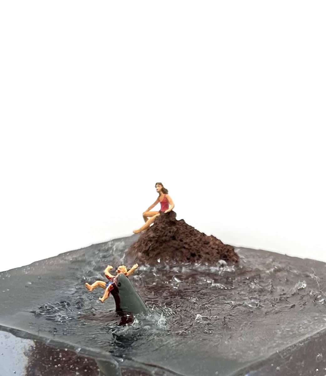 sculpture of a woman on a rock and another woman being eaten by a shark in the water