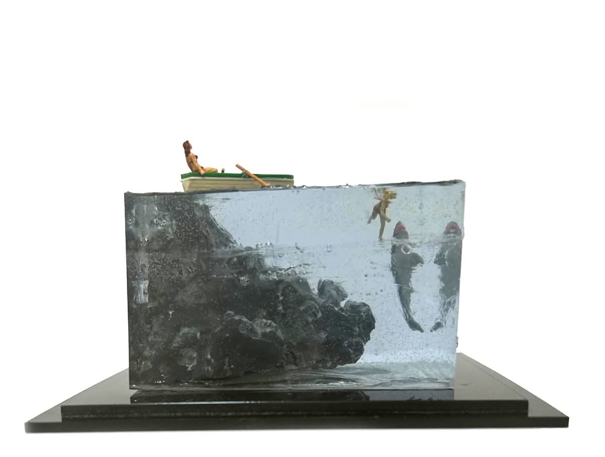 sculpture of a person rowing a boat and another person swimming with a shark coming to eat them