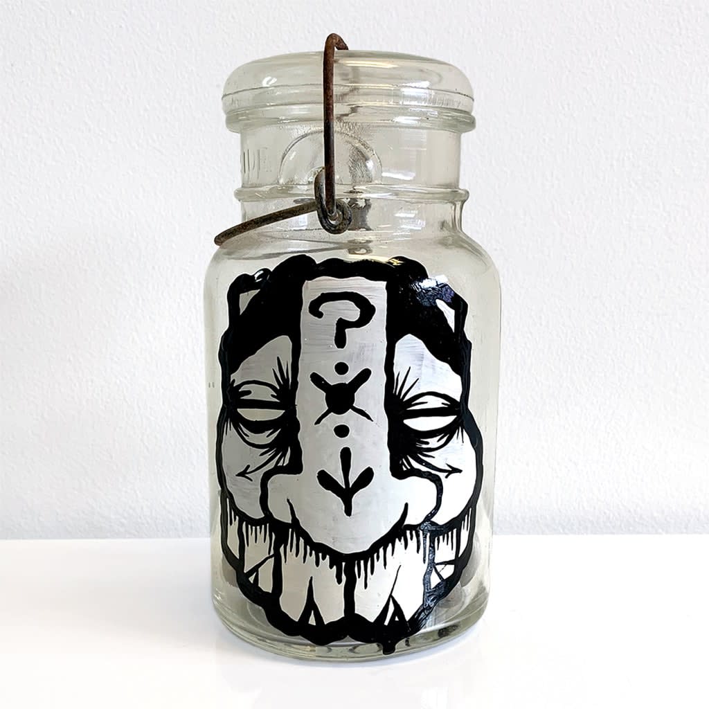 A glass jar with an abstracted masculine face decorated with details (symbols, patterns).