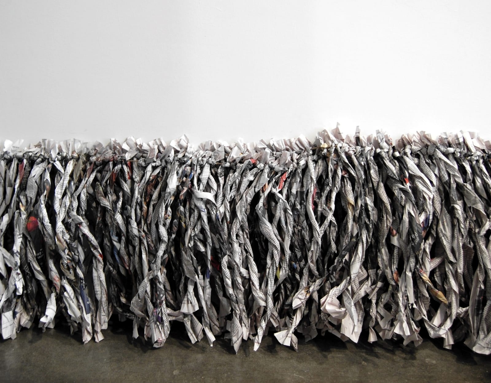 Twisted newspaper strips strung together and lining lower edge of wall touching floor