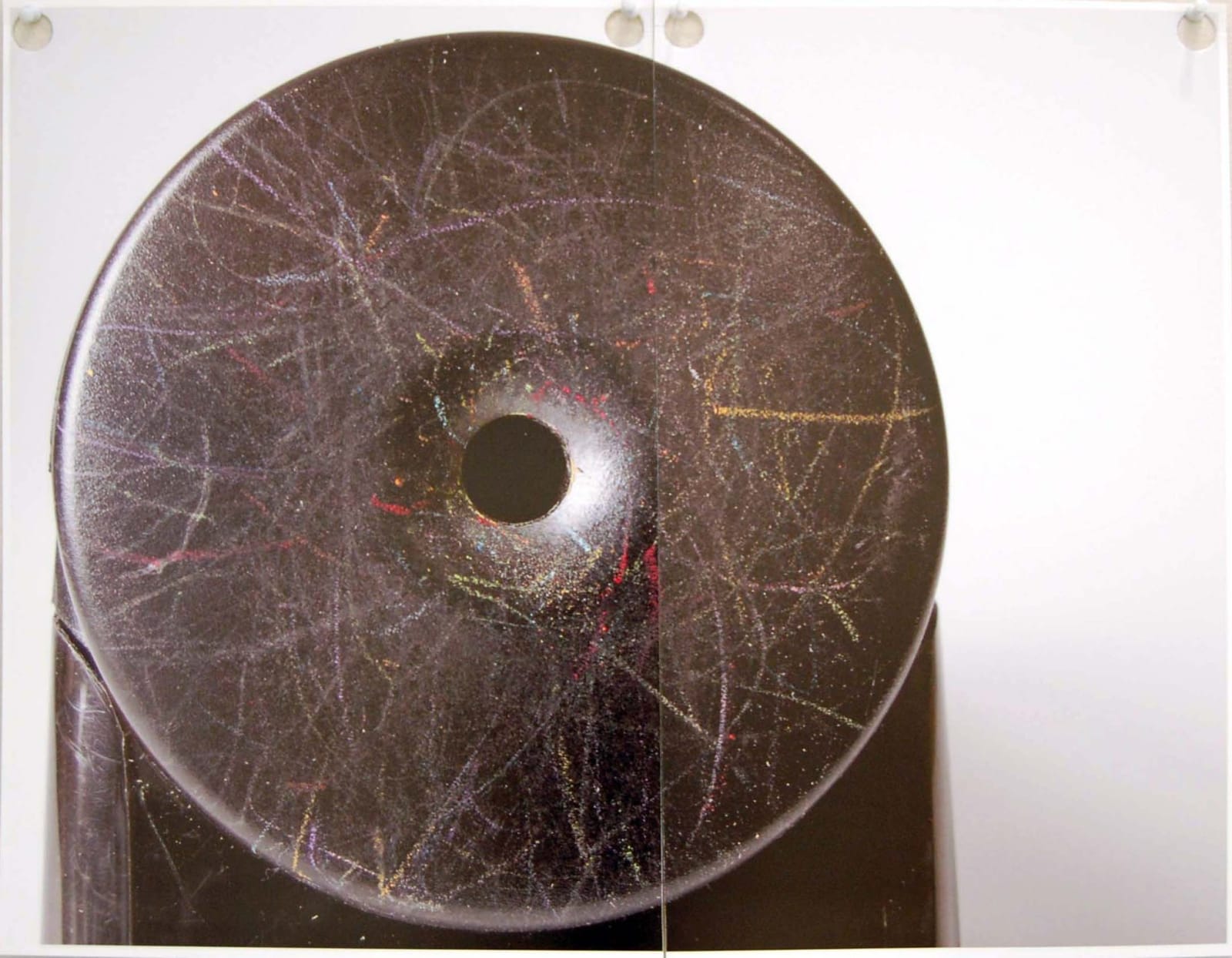 Circular stone sculpture with a hole in the center and a scratched surface