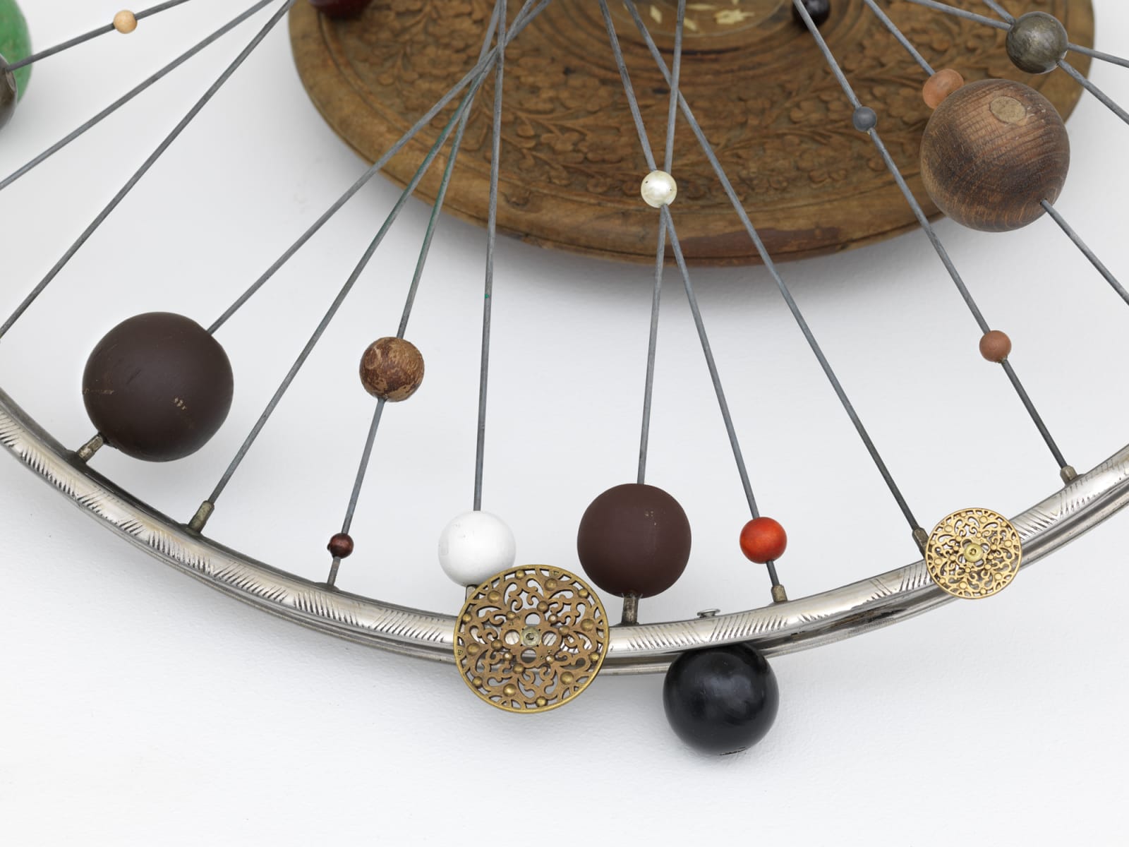 Detail of a bicycle wheel adorned with delicately carved orbs of varying sizes