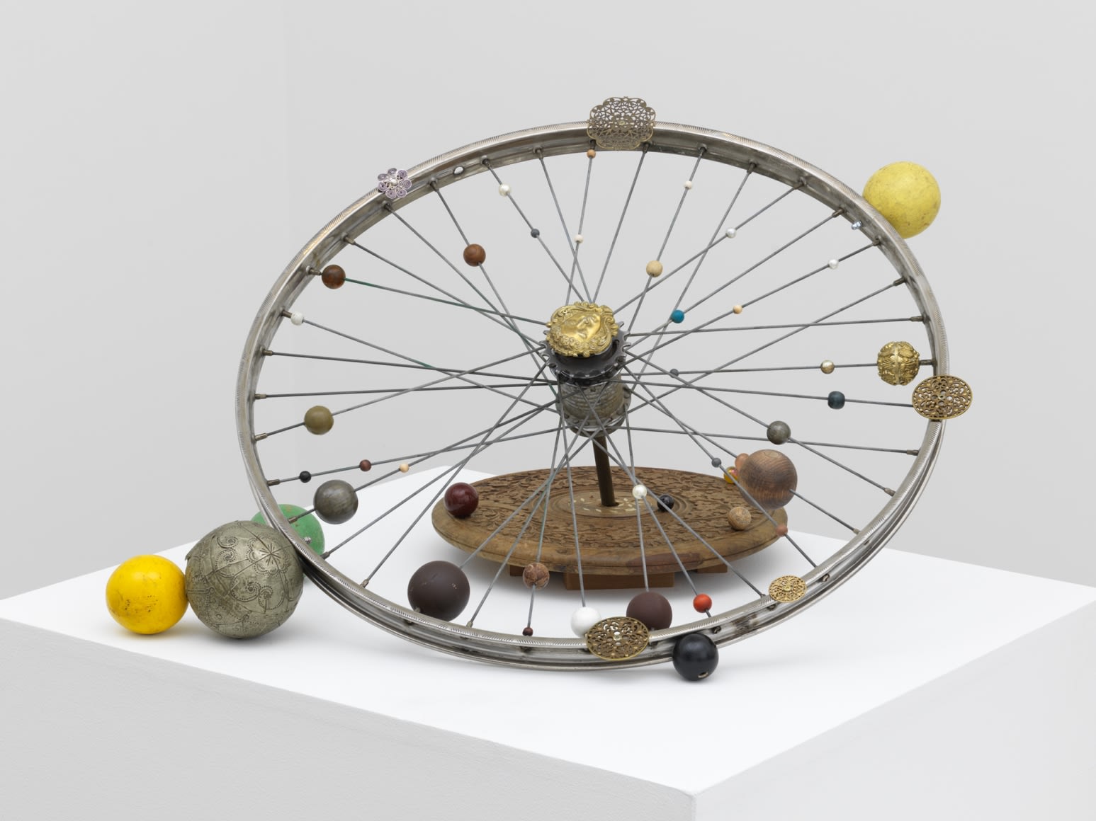 A bicycle wheel adorned with delicately carved orbs of varying sizes